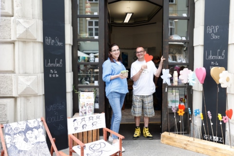 Der LebensGroß Pop-Up Store in der Grazer Herrengasse von außen, im Eingang stehen lächelnd eine Frau und ein Mann