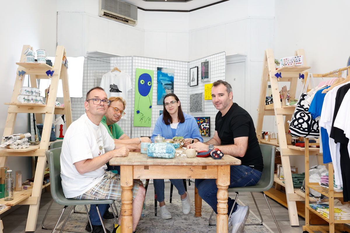 LebensGroß Teilnehmer:innen und Begleiter:innen arbeiten gerade sitzend an Tisch im Pop-Up Store